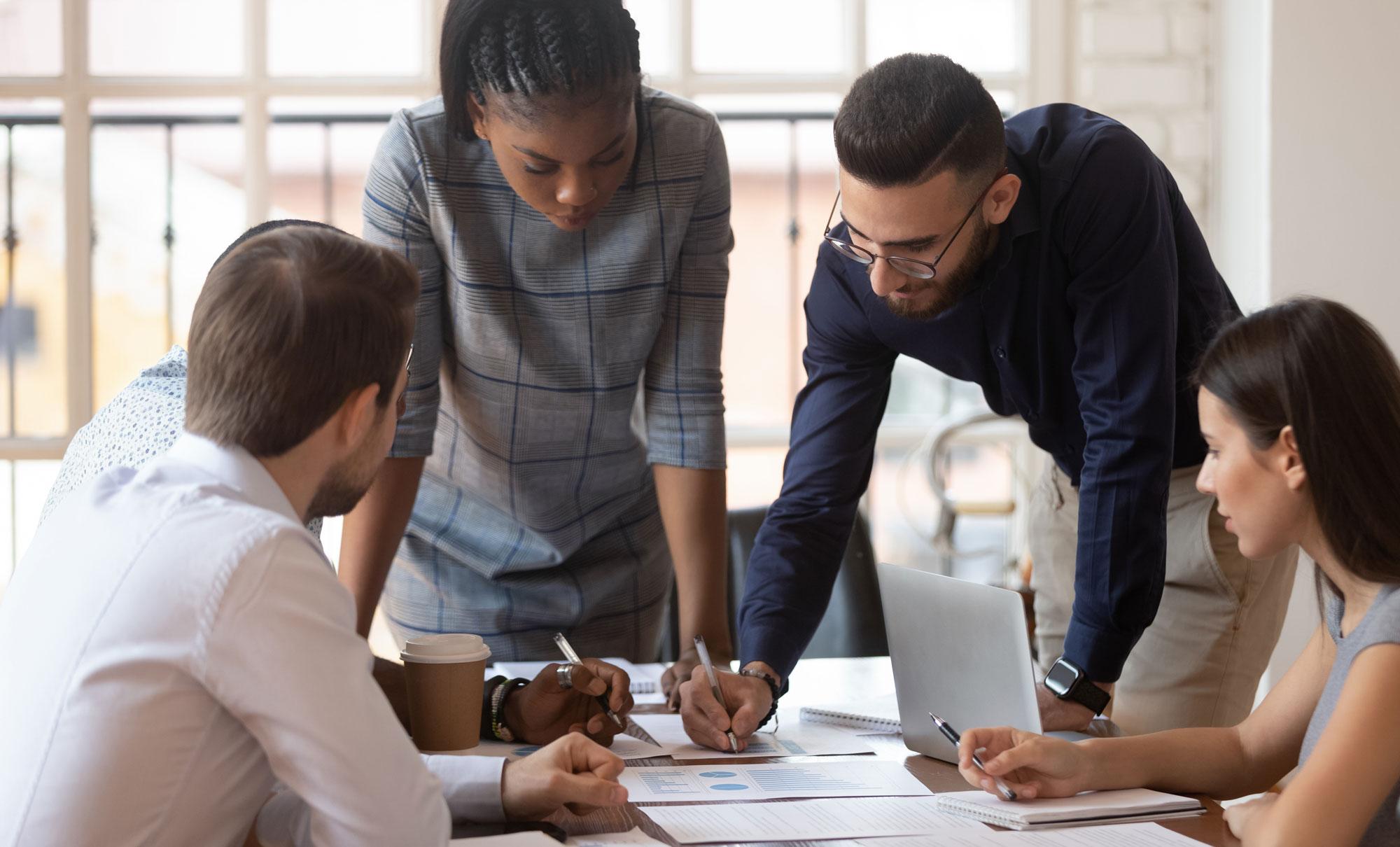 Five people sitting around a desk working on a business plan