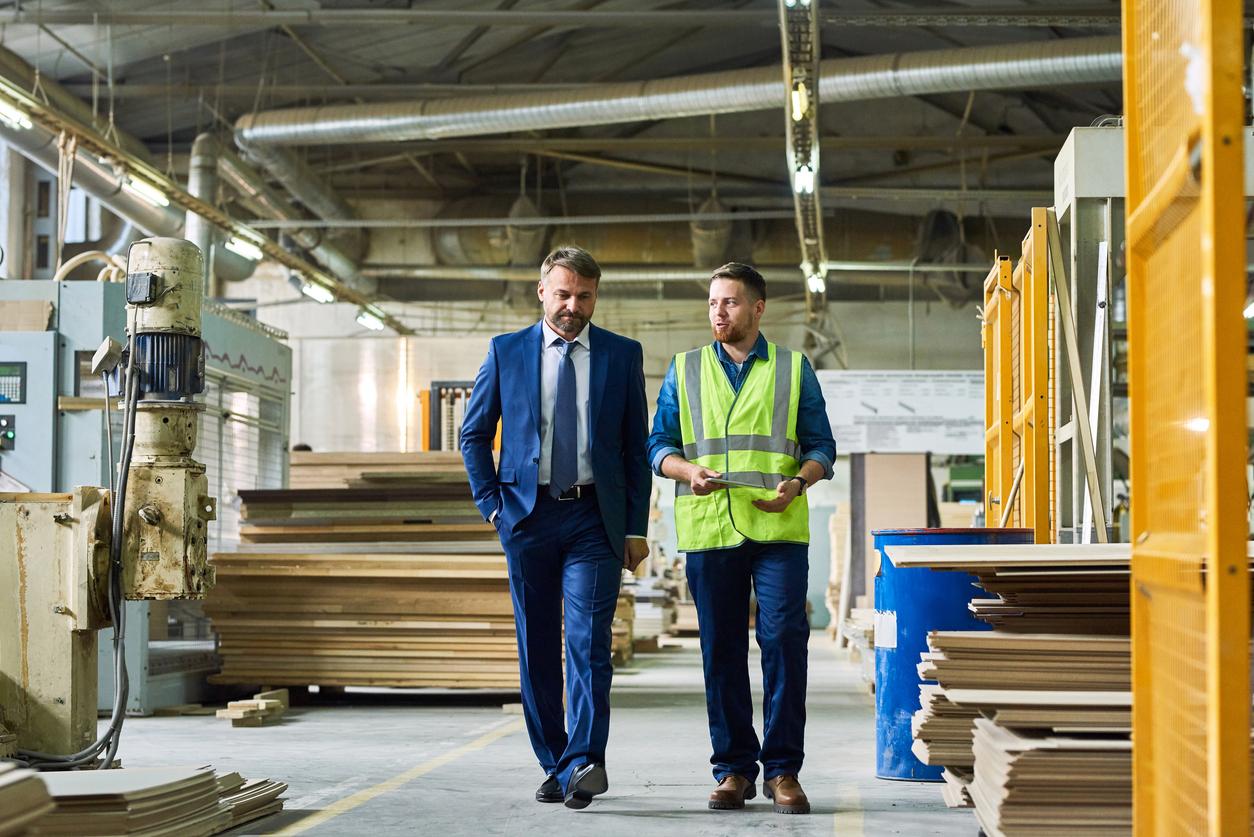 A man in a suit and a man in a vest walk through a warehouse based in a Foreign-Trade Zone