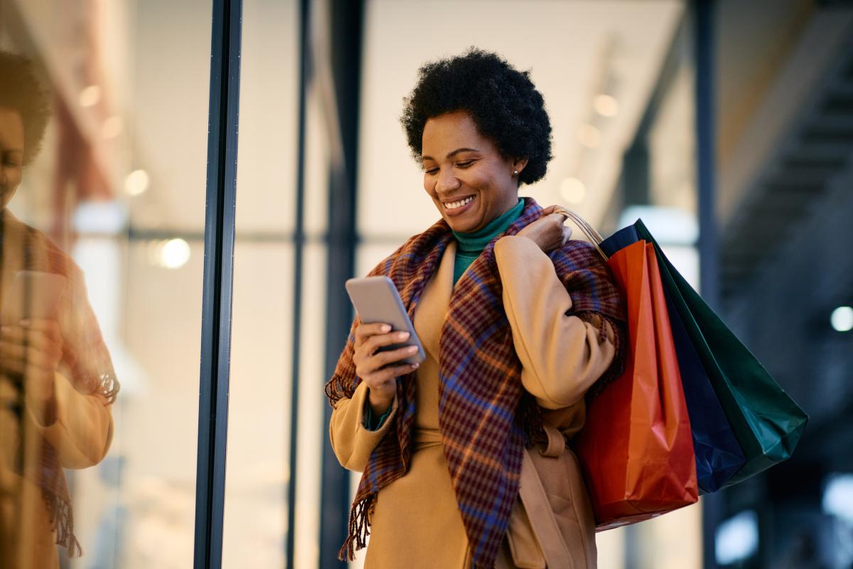 Smiling woman holding bags while shopping in Lakewood. 