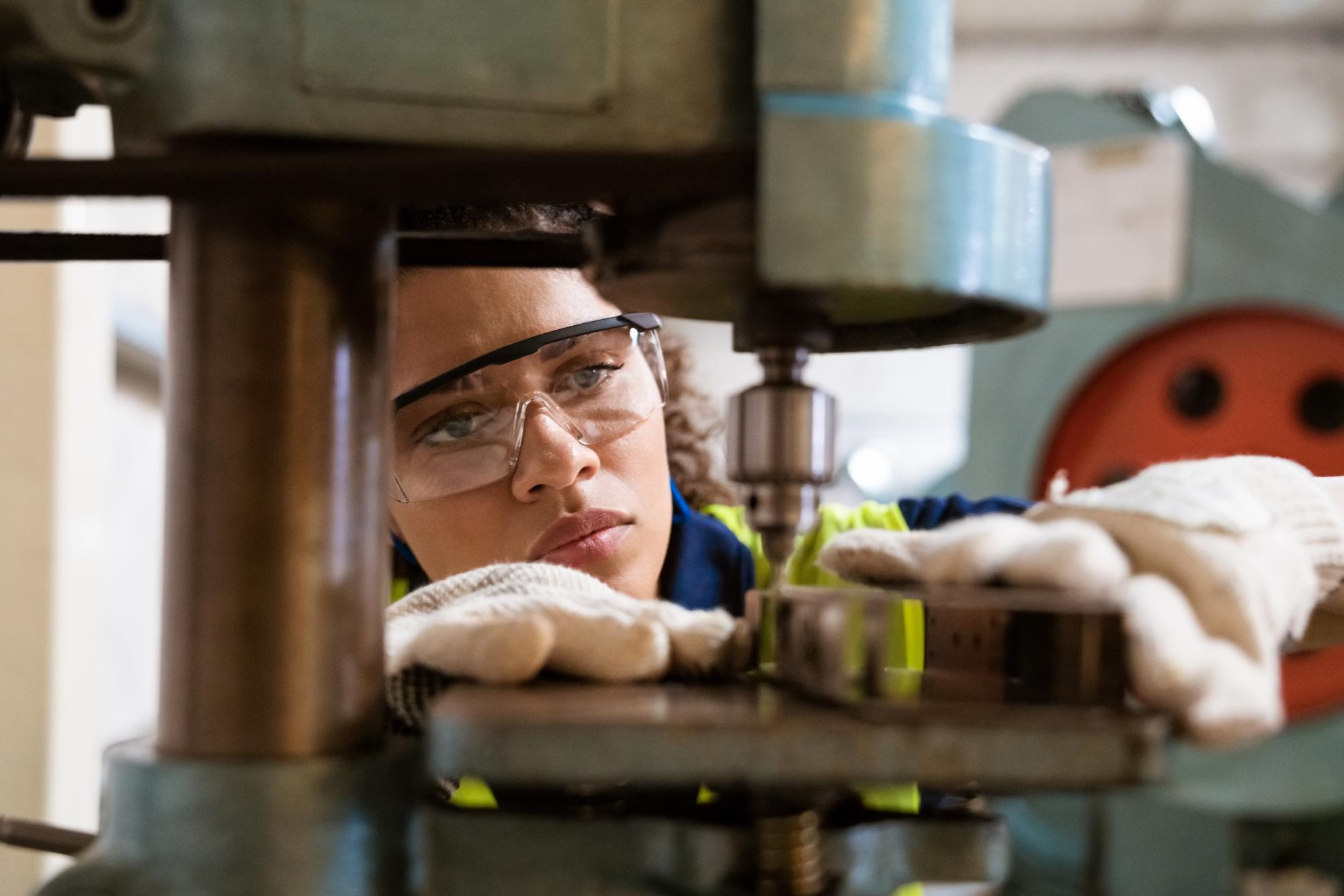 Woman in advanced manufacturing program in Lakewood carefully aligns equipment. 